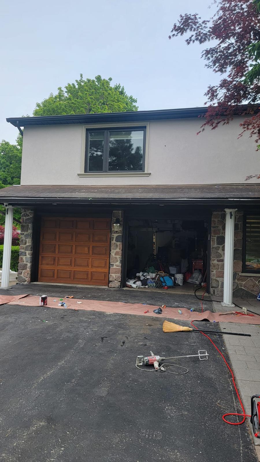 Classic home with wood garage door and stone-clad columns
