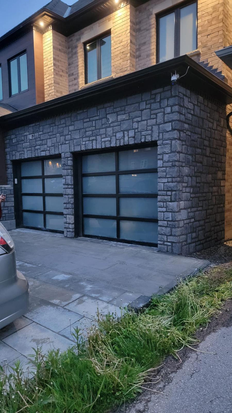 Stone garage exterior at dusk with glass-panel doors