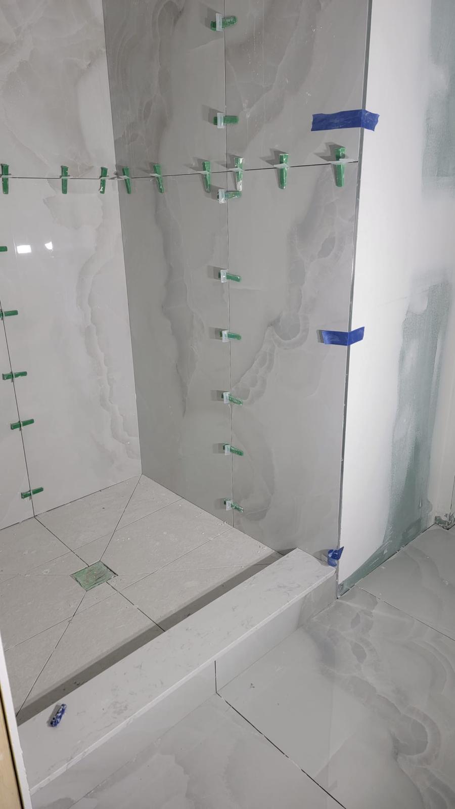 Grey-veined marble shower install with glass divider