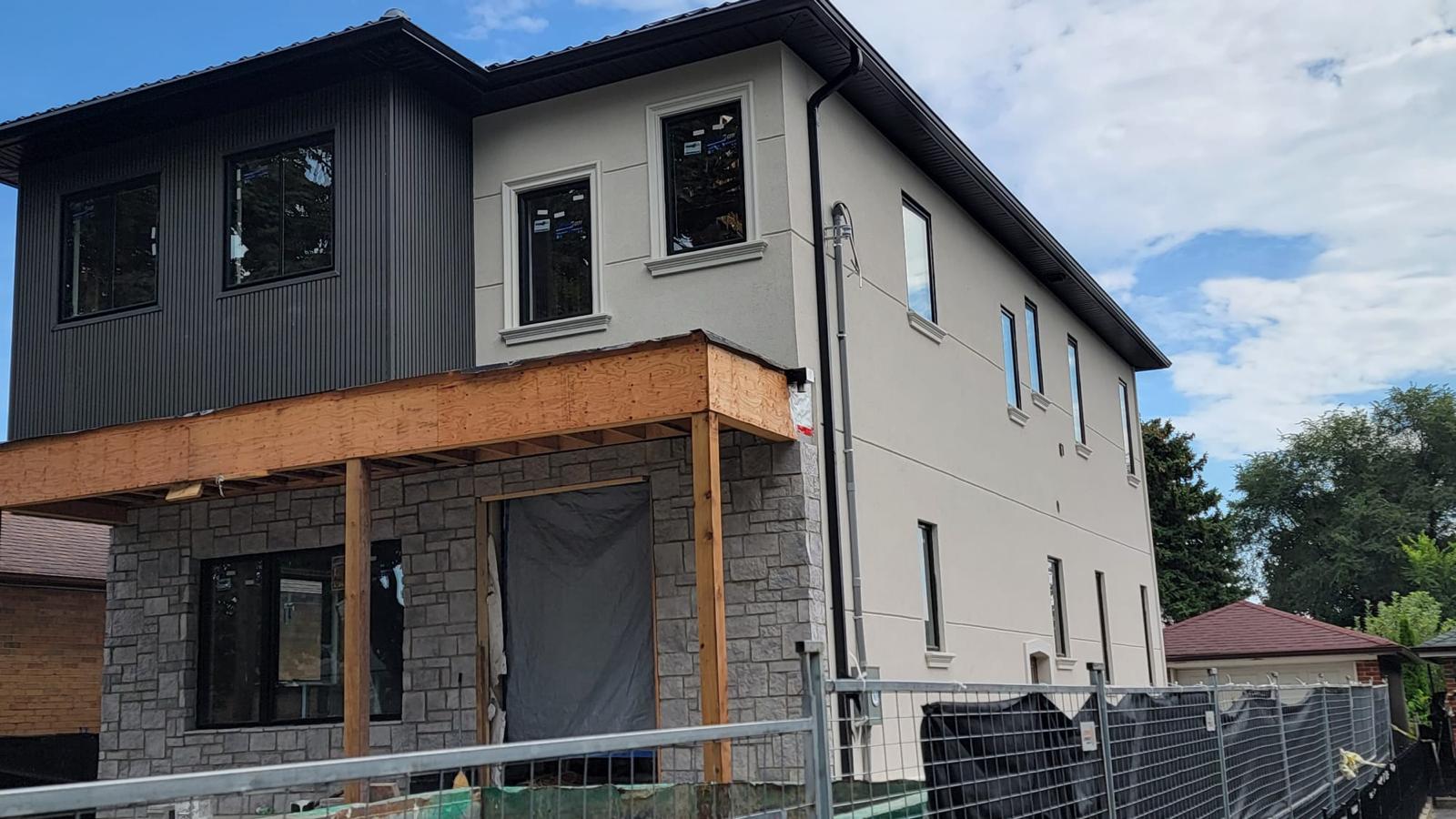 Modern two-tone home with dark vertical siding and stone base