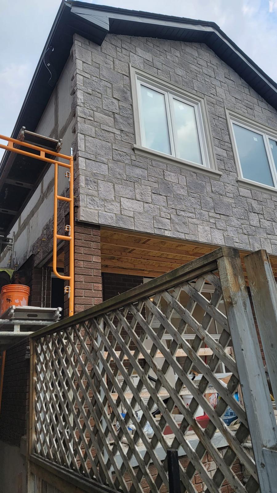 Grey stone-clad rear addition under construction
